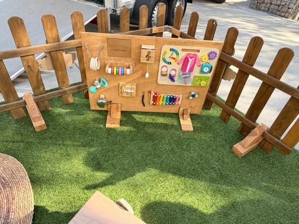 Descubrir con las manos Panel sensorial de madera con engranajes, cierres, campana y xilófono.